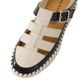 A pair of Django & Juliette Baytown Black Almond patent leather flats featuring closed toes, woven leather straps, a black stitched edge, and a side silver buckle.