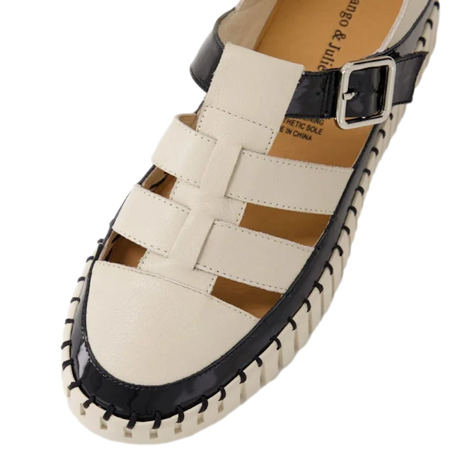 A pair of Django & Juliette Baytown Black Almond patent leather flats featuring closed toes, woven leather straps, a black stitched edge, and a side silver buckle.