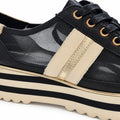 Close-up of the Django & Juliette Eminta Platform Shoe Sheer Leather Black Milk Lace Up featuring beige stripes, gold accent, sheer side panels, and a chunky beige and black striped serrated platform sole.
