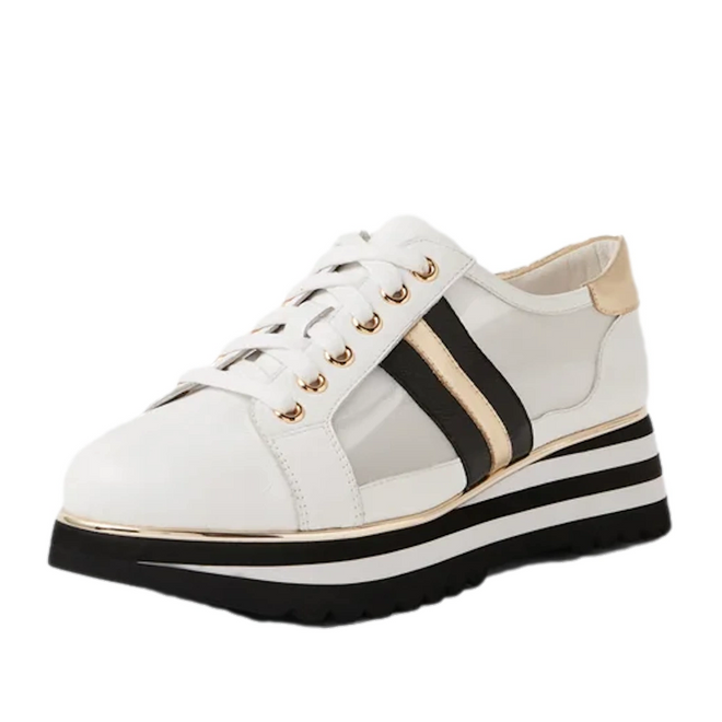 The Django & Juliette Eminta Platform Shoe is a white women’s lace-up sneaker featuring gold eyelets, black and gold side stripes, sheer leather side panels, and a bold black-and-white striped platform sole.