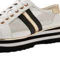 Introducing the Django & Juliette Eminta Platform Shoe: a white leather women’s sneaker with black laces, gold and black accent stripes, gold eyelets, and a thick platform sole featuring black, white, and gold layers. This stylish lace-up design also includes sheer side panels for a contemporary look.