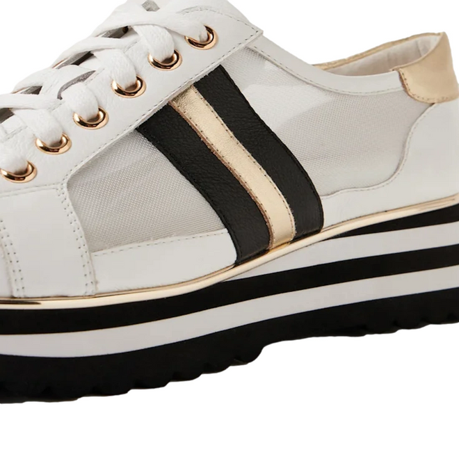 Introducing the Django & Juliette Eminta Platform Shoe: a white leather women’s sneaker with black laces, gold and black accent stripes, gold eyelets, and a thick platform sole featuring black, white, and gold layers. This stylish lace-up design also includes sheer side panels for a contemporary look.