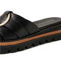 A close-up of the Django & Juliette Scoop Platform Slide Black—a stylish women’s leather slide featuring a thick, ridged black platform sole, tan stripe detail, and a gold accent on the upper strap.