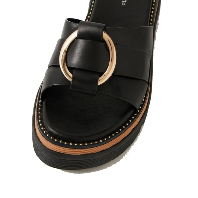 Introducing the Django & Juliette Scoop Platform Slide Black: a women’s leather platform slide sandal in black, featuring a wide strap, gold circular buckle detail, wooden accent midsole, and decorative gold studs along the edge.