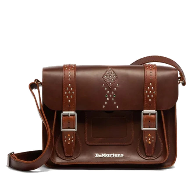The Dr. Martens Leather Cross Body in Amber Tan features rivets, jeweled details, a shoulder strap, buckle fastening with silver buckles, and the embossed Dr. Martens logo on the front.
