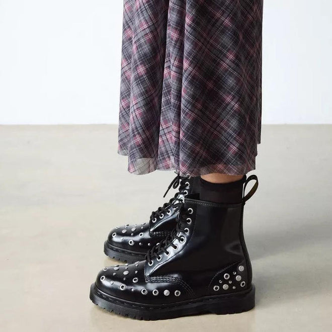 A person wearing a long plaid skirt and shiny black Dr Martens 1460 Hardware HDW Buttero Leather Boots stands on a light-colored floor., 49862, 190665797572, 190665797589, 190665797602, 49866, 49867, 49868, 49869