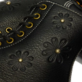 Close-up of black Grizzly leather on the Dr. Martens Women's 1460 Pascal Flower Boot, featuring decorative flower patterns, gold eyelets, and white stitching., 52216, 190665781137, 190665781144, 190665781151, 190665781175, 190665781182, 52222
