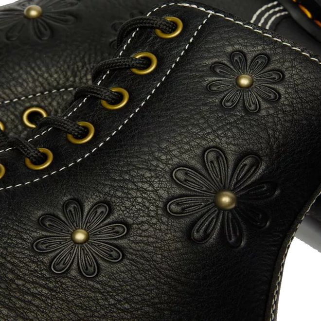 Close-up of black Grizzly leather on the Dr. Martens Women's 1460 Pascal Flower Boot, featuring decorative flower patterns, gold eyelets, and white stitching., 52216, 190665781137, 190665781144, 190665781151, 190665781175, 190665781182, 52222