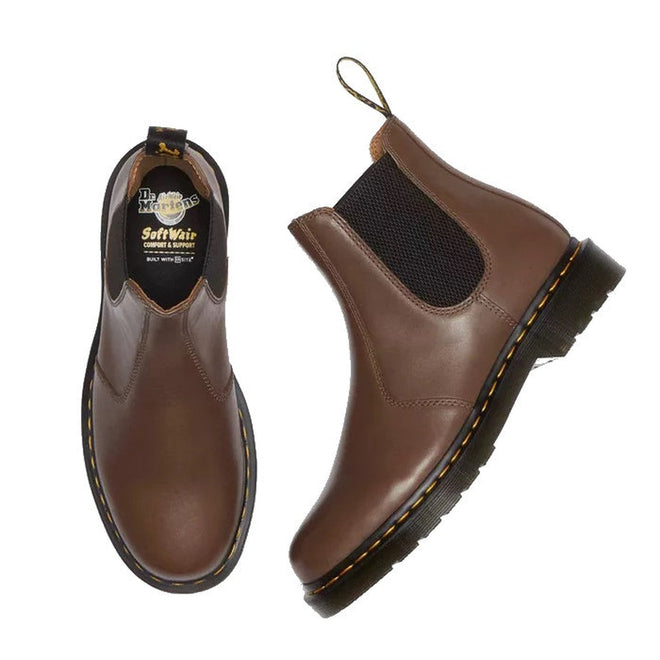 The Dr. Martens 2976 YS Chelsea Boot in Dark Khaki Legacy Brown features black elastic side panels, yellow stitching, a rear loop, and visible insole branding—one boot stands upright while the other displays the top view.
