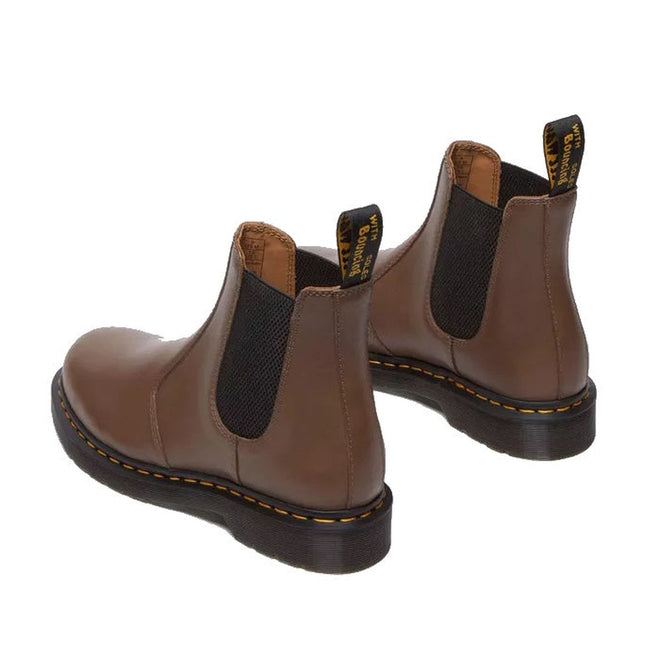 The Dr Martens 2976 YS Chelsea Boot in Dark Khaki Legacy Brown features black elastic side panels, yellow stitching on the AirWair sole, and black pull tabs with yellow branding.