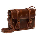 The Dr Martens Leather Cross Body Amber Tan Leather Satchel 7 inch features white stitching, two buckled front straps, a long adjustable shoulder strap, and embossed flower designs on the flap and front.
