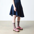 A person wearing a dark blue dress, sheer gray ankle socks, and Dr. Martens 8065 2 Strap Mary Jane Shoe in Dusky Rose Pink stands on a beige floor against a plain white background., 50241, 50242, 50243, 50244, 50245, 50246, 50247, 50241, 190665781861, 190665781878, 190665781892, 50245, 50246, 50247