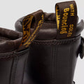 Close-up of the back of two Dr Martens Anistone Harness Bex Crazy Dark Brown Horse Biker Boots, made from Crazy Horse leather, featuring yellow and black pull tabs with "WITH BOUNCING SOLES" in yellow text., 49399, 190665745689, 190665745696, 190665745719, 49407, 49409, 49411, 49412
