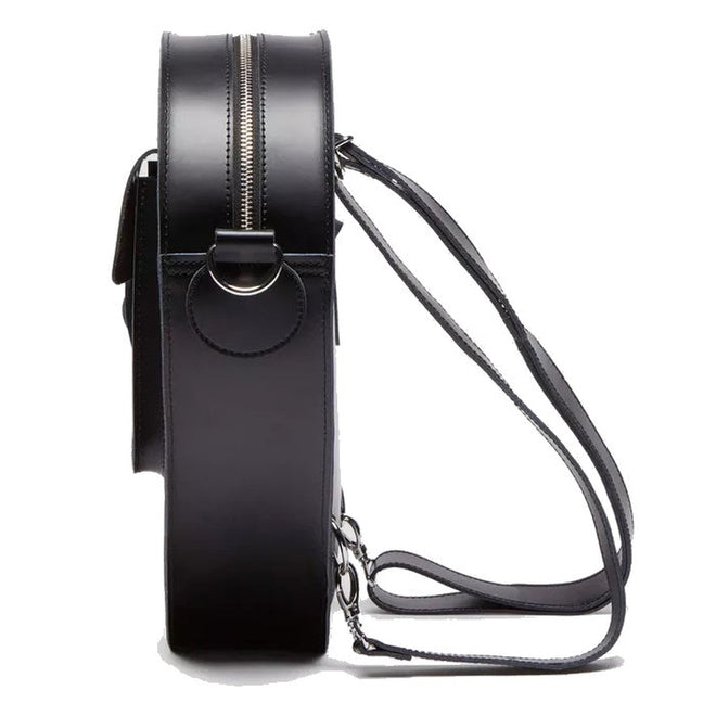 A side view of the Dr Martens Large Big Heart Box Backpack in black leather, featuring a zipper closure, adjustable straps, metal rings, and minimalist design details in the brand's signature style., 190665665406