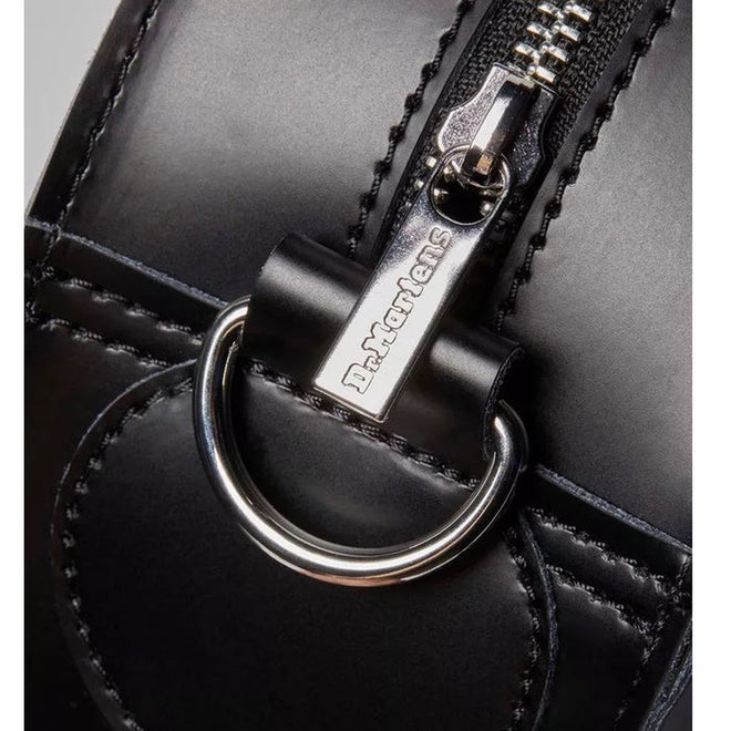 Close-up of a black leather Dr. Martens shoe with silver zipper, metal D-ring, visible stitching, and Dr. Martens logo on the pull—pairs perfectly with the Dr Martens Large Big Heart Box Backpack Leather Black., 190665665406