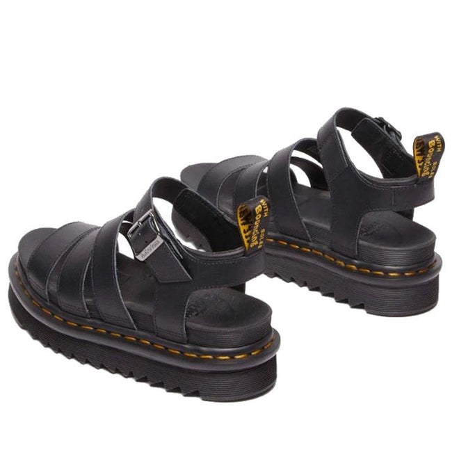 A pair of Dr Martens Blaire Sandals on a white background, showing from the heels to the front. Seeing the outer foot side of the left foot and the inner side view of the right foot and bakc strap with dr martens iconic pull tab and yellow stitching around the sole.,
190665725629,
190665725636,
190665725643,
190665725667,
190665725674,
190665725681,