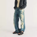A person wearing baggy, distressed blue jeans with bleach stains and black Dr Martens Clarissa II Quad Platform Sandal sandals.