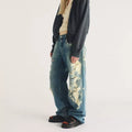 A person wearing wide-leg distressed jeans with bleach spots and black Dr Martens Clarissa II Quad Platform Sandal sandals.