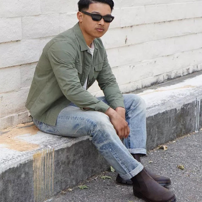 A lifestyle shot man wearing blue jeans, a green jacket and white t-shirt sitting on a concrete step wear Dr Martens Embury chelsea boots in crazy horse dark brown.,
190665358643,
190665358650,
190665358674,
190665358681,
190665358698,
190665358711,