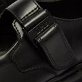 Close-up of the Dr Martens Bex Indica II Mary Jane Tech Nappa Mono Black, featuring a metal DMS-engraved buckle, precise stitching, and a smooth black leather finish., 190665804744, 190665804751, 190665804768, 190665804782, 190665804799, 190665804805, 50377