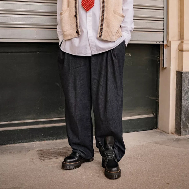 A person is seen outdoors in loose dark pants and black Dr Martens - Jadon Polished Smooth Boot 8 up, styled with a white shirt, cream sleeveless sweater, and red tie. The cropped photo shows only their lower half., 883985578883, 883985578890, 883985578906, 883985578913, 883985578920, 883985578937, 883985578944, 883985578951, 883985578975, 883985578968