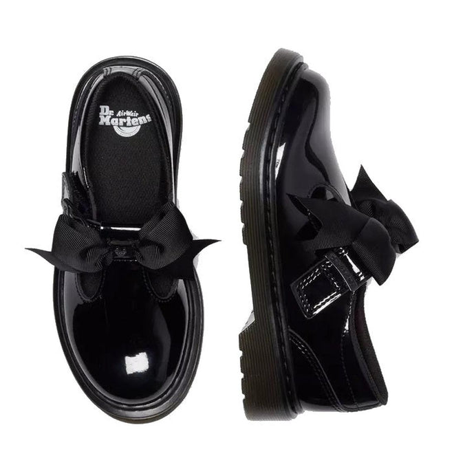 A flay lay of a pair of Dr Martens Kids Polley Bow Black patent leather shoes with bows on a white background. The right foot top down showing the Dr Martens ogo on the footbed, The left foot showing the outer.,
190665761818,
190665761832,
190665761856,
190665761863,
190665761764,
190665761788,
190665761801,