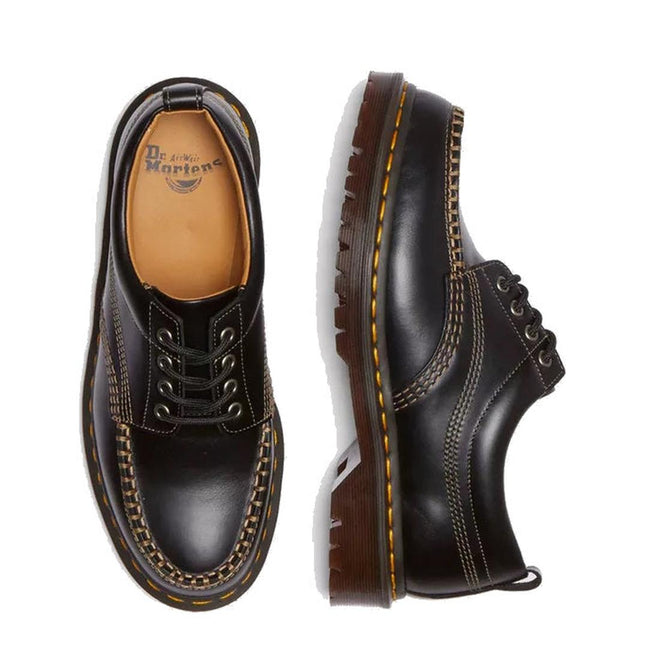 The Dr. Martens Lowell Moc Toe Black Leather Shoe features analine leather, yellow stitching, thick brown soles, and contrasting white details, shown from top and side views on a white background., 50395, 50396, 50397, 50398, 50399, 190665668940, 190665668957, 190665668971, 190665668988, 50404