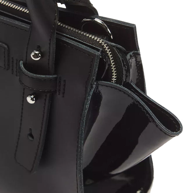 Close-up of the Dr Martens Small Keiv Leather Tote Bag in black, highlighting its handle with patent Lamper straps, silver zipper, metal studs, and glossy-finished side panel.