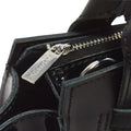 Close-up of the Dr Martens Small Keiv Leather Tote Bag in black, featuring a shiny patent leather surface and detailed stitching. The silver zipper pull, engraved with Dr. Martens, is visible, while sleek patent Lamper straps enhance the bag’s modern aesthetic.