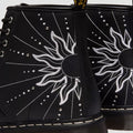 Close-up of the Dr Martens 1460 Genix Solar Flare Black 8 Up Eye Boot, made in Genix Nappa leather with black uppers, white embroidered sun and ray details, silver studs, and classic stitching for a bold artistic look., 190665742824, 190665742831, 190665742848, 190665742862, 190665742879, 190665742886
