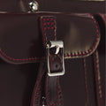 Close-up of the Dr Martens Top Handle Bag in Cherry Red Oxford Rub Off leather, featuring a shiny silver buckle and maroon stitching, showcasing detailed craftsmanship and the rich texture inspired by the classic oxford rub off finish.