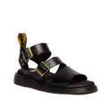 The Dr Martens Gryphon Sandal Black Atlas Leather features two gold buckles, a thick Goodyear welted sole, open toes, and a yellow-branded pull tab at the heel.