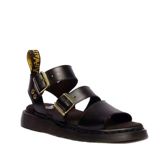 The Dr Martens Gryphon Sandal Black Atlas Leather features two gold buckles, a thick Goodyear welted sole, open toes, and a yellow-branded pull tab at the heel.