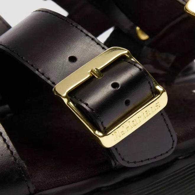 Close-up of the Dr Martens Gryphon Sandal in black Atlas leather, featuring gold buckles engraved with “BIRKENSTOCK,” visible stitching, and a dark, cushioned footbed for comfort., 190665783414, 190665783421, 190665783438, 190665783452, 190665783469, 50536