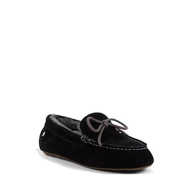 The side and front view of an EMU sandrine black moccasin-style sheepskin slipper with a bow detail on the top and a visible rubber sole.