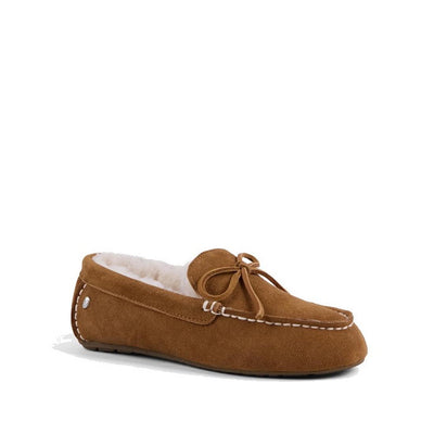 the right foot showing the side nad front of a chestnut tan moccasin-style sheepskin slipper with a bow detail on the top and a visible rubber sole.