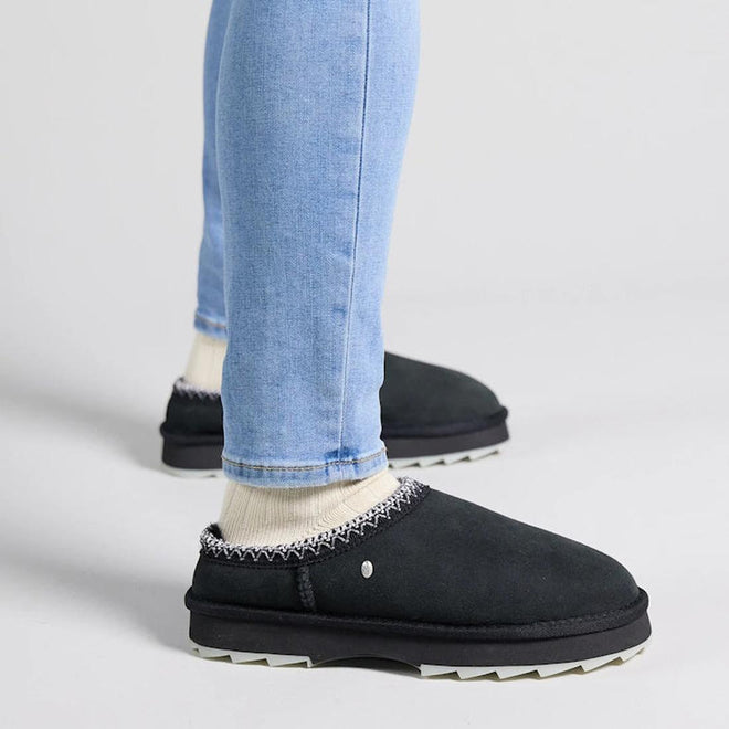 Person wearing black  EMU Outack Sharky Scuff Mule slippers with chunky  white soles on a light gray background.,
9330071973073,
9330071973080,
9330071973097,, 45243, 9330071973073, 9330071973080, 9330071973097, 45247, 45248