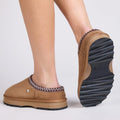 Tan EMU Sheepskin Outback Mule Sandl slippers on a modal looking from the back view in a walking poise showing the chunky serrated black sole  on a light gray background.,
9330071968499,
9330071968505,
9330071968512,
9330071968529,, 45249, 9330071968499, 9330071968505, 9330071968512, 9330071968529, 45254