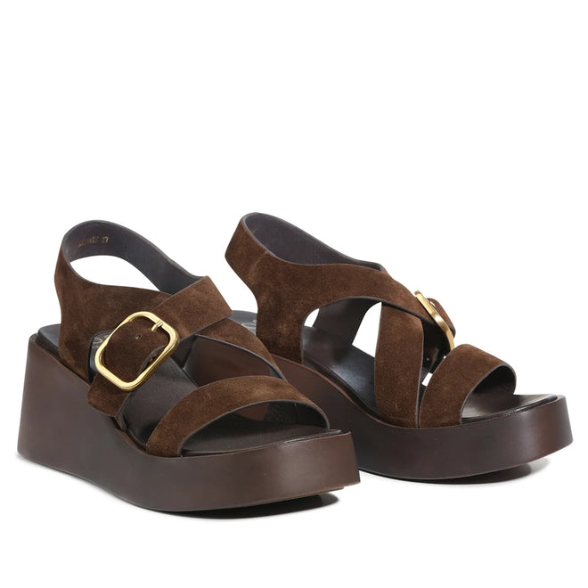 Introducing the EOS Arianis Chestnut Brown Women’s Suede Leather Wedge Sandals—crafted from premium suede leather, these stylish sandals feature crisscross straps with gold buckles and thick dark brown wedge soles. Designed with an anatomical footbed, they offer all-day comfort and effortless style.