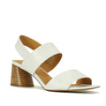 The EOS Peto White Leather Sandal features a wide toe strap, back strap over the ankle, low chunky heel, tan inner lining, and is shown against a plain white background.