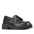 The EOS Womens Leia Loafer Slip In Black Leather is a black loafer with a chunky cleated heel and decorative buckle, shown against a white background.