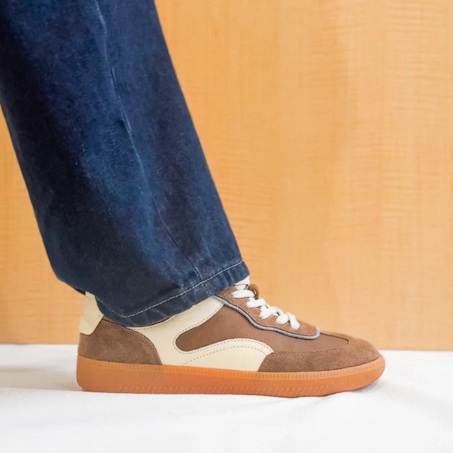 A person wearing wide-leg blue jeans and EOS Antigona Pecan Leather Lace up Trainers stands on a white surface against a light wood background., 50069, 9321190000733, 9321190000740, 9321190000757, 9321190000764, 9321190000771, 50075