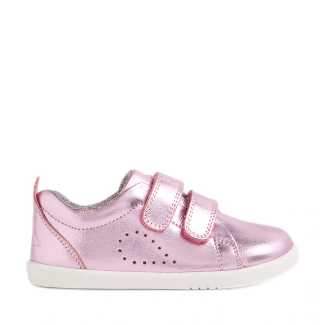 The Bobux Iwalk Toddlers Grass Court Pink Metallic Leather Trainer features shiny pink leather, two Velcro straps, small perforated side holes, a cushioned collar, and a white rubber sole—shown in profile on a white background. Perfect toddler trainers inspired by the classic Bobux Grass Court style.