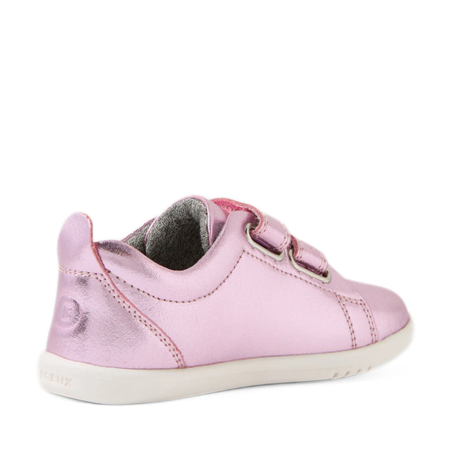 The Bobux Iwalk Toddlers Grass Court Pink Metallic Leather Trainer is a kids’ sneaker featuring two velcro straps, a bright white sole, and a stylish low-back heel. Shown from an angled rear view, this modern shoe stands out with its shiny metallic pink leather and design inspired by the iconic Bobux Grass Court trainers.