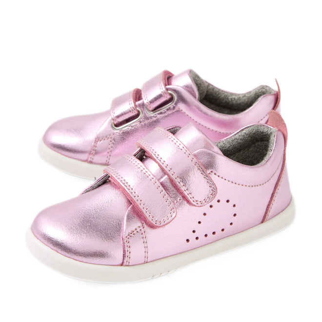 Shiny pink metallic toddler shoes with white soles, featuring two velcro straps and small perforated dots on the side for decoration, these Bobux Iwalk Toddlers Grass Court Pink Metallic Leather Trainers are perfect kids’ leather sneakers for everyday adventures.
