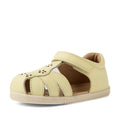 The Bobux IWalk Holly Toddlers Sandal in Wax Yellow is a light yellow closed-toe sandal for toddlers, made from quick-drying leather. It features cutout sides, floral cutout details on the front, and a Velcro strap for easy fastening—all showcased against a white background.