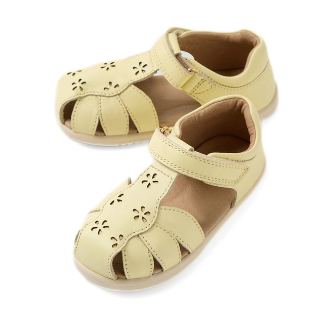 A pair of Bobux IWalk Holly Toddlers Sandal Wax Yellow Closed Toe, featuring quick-drying light yellow leather with flower-shaped cutouts and a Velcro ankle strap, displayed on a white background.