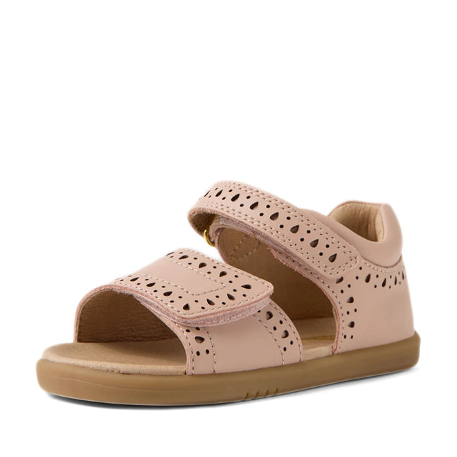 The Bobux IWalk Logan Toddlers Sandal in Cameo Rose Pink is an open-toe sandal for toddler girls, featuring decorative cut-out patterns, adjustable Velcro straps, and a flat light brown rubber sole.
