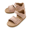 A pair of Bobux IWalk Logan Toddlers Sandal in Cameo Rose Pink, featuring open toes, perforated patterns, and Velcro straps. These tan-colored leather sandals include a soft cushioned footbed for added comfort.