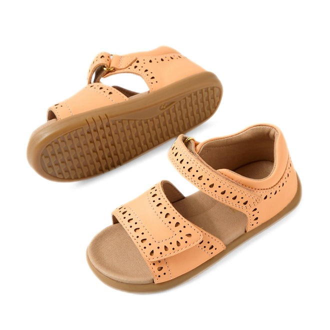 A pair of Bobux IWalk Logan Toddlers Sandal Peach Jelly Open Toe for girls, featuring a peach color, cutout details, Velcro straps, and durable rubber soles. These leather sandals are both stylish and practical—one sandal is displayed upright while the other lies on its side to showcase the tread pattern.